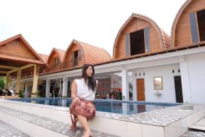 a woman sitting on a ledge in front of a building at Garuda Hostel & Accomodation Nusa Penida in Nusa Penida