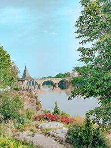 un pont sur une rivière avec des fleurs et un pont dans l'établissement Le Vin Quatre, à Bergerac