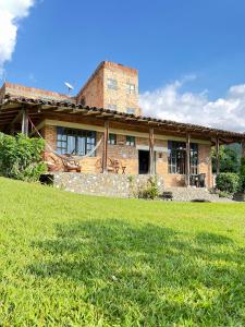 a large brick house with a grass field in front of it at Ventanas Parapente Boutique - Club House in El Cerrito