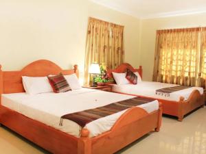 a bedroom with two beds and a room with two windows at Keanthay Guest House in Battambang