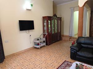 een woonkamer met een bank en een tv aan de muur bij G & S Executive Lodge in Dar es Salaam