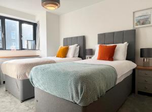 ペンザンスにあるBeautiful 3 Bed Townhouse with Parking, close to Sea Frontのベッドルーム(オレンジ色の枕付)のベッド2台