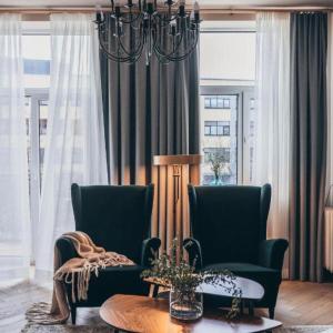 a living room with two chairs and a chandelier at Lindens apartments in the heart of the city in Panevėžys