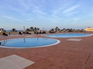a swimming pool in a patio with people sitting around it at Ocean Breeze in Ras al Khaimah