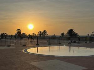 a swimming pool with the sunset in the background at Ocean Breeze in Ras al Khaimah