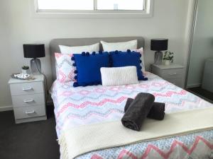 1 dormitorio con 1 cama con almohadas azules y blancas en Discover Warilla - Bright and Airy Townhouse near the Beach and Lake, en Lake Illawarra