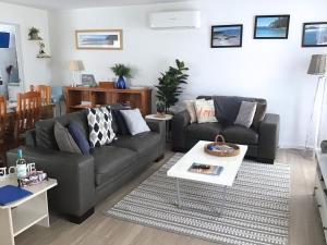 ein Wohnzimmer mit einem Sofa und einem Tisch in der Unterkunft Discover Warilla - Bright and Airy Townhouse near the Beach and Lake in Lake Illawarra