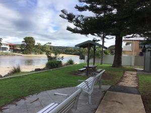 a park with two benches and a table and an umbrella at Discover Warilla - Bright and Airy Townhouse near the Beach and Lake in Lake Illawarra