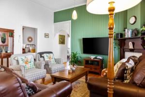 a living room filled with furniture and a flat screen tv at Ambiente Cottage - Pet and Family Friendly in Toowoomba