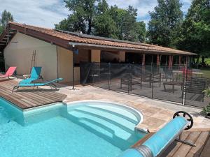 a swimming pool with a patio and a house at La chambre du Gaille in Captieux