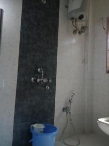 a bathroom with a shower and a bucket in it at Govindaashram in Bhogwe