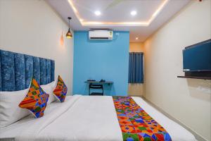 1 dormitorio con 1 cama con pared azul en FabHotel Grand Broholic, en Hyderabad