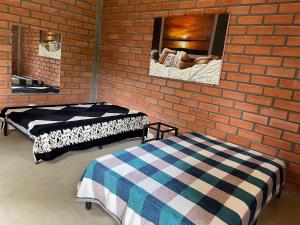 two beds in a room with a brick wall at Condominio la laguna in La Rochela
