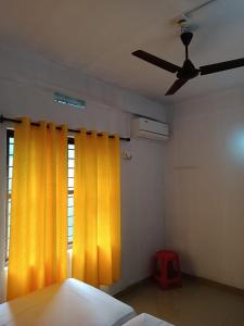 a bedroom with yellow curtains and a ceiling fan at KK Residency in Perintalmanna