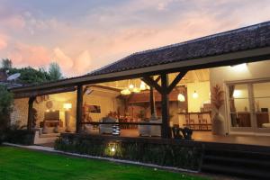 een huis met een overdekte patio met een tuin bij Villa Tabatha by Optimum Bali Villas in Seminyak