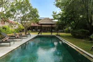 a swimming pool with chairs and a gazebo at Villa Tabatha by Optimum Bali Villas in Seminyak