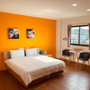 1 dormitorio con pared de color naranja, cama y mesa en Hospitality Hotel, en Xiaoliuqiu