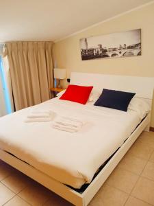 a bedroom with a large white bed with red and blue pillows at Residenza Villa in Corno Alto
