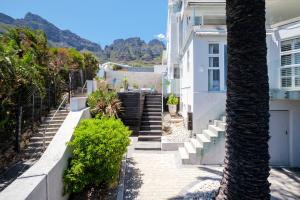 a white house with stairs and a palm tree at Beach Steps in Cape Town