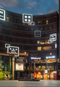 um grande edifício com cartazes à noite em Wuyu Hotel - Chongqing Liangjiang Happiness Plaza em Chongqing