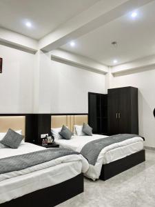 two beds in a room with white walls at Dhaneshwari Homestay in Varanasi