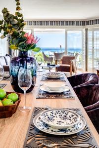 a dining room table with plates and a vase of flowers at Beach Steps in Cape Town