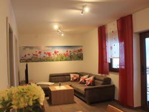 a living room with a couch and a painting of flowers at Preuschens Hof in Egloffstein