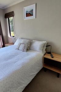 a bedroom with a white bed and a window at Private guest room - no kitchen in Wanaka