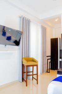 a room with a bed and a yellow stool and curtains at Ceylanro Transit Villa in Negombo