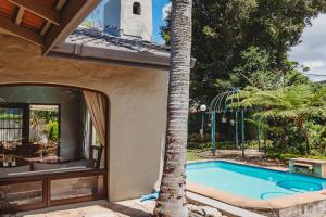 a swimming pool next to a house with a palm tree at Rusgenot- perfect family home in George