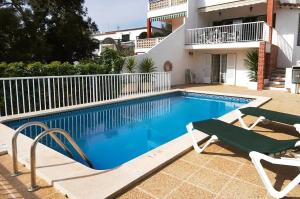 a swimming pool with two chairs and a house at Ca n'Ernest in Cala Galdana