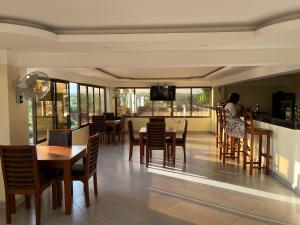 a dining room with tables and chairs and a woman at THE AVID HOTEL in Voi
