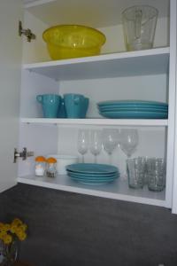 a shelf with plates and bowls and glasses on it at Mieszkanie Przy Plaży in Gdańsk