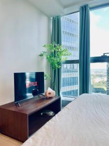 a bedroom with a bed and a tv and a window at Thompson Suites - 2 beds, Uptown Parksuites Tower 1 25F in Manila