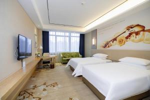 a hotel room with two beds and a flat screen tv at Vienna International Hotel Hengyang Huayao city in Hengyang