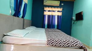 a bed in a room with blue walls and curtains at Ashirwad Cottage in Matheran