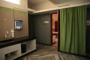 a bathroom with a green shower curtain and a sink at Gs Gardenia Homestay in Madurai