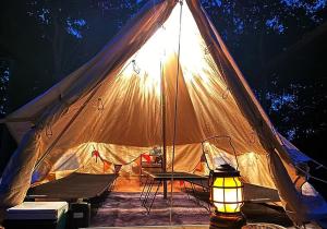 ein beleuchtetes Zelt mit einem Tisch und einer Lampe in der Unterkunft Katsuyama Basecamp - Camp - Vacation STAY 42349v in Yamanuha