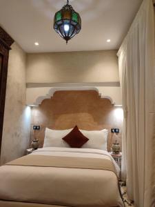 una camera con un grande letto e un lampadario a braccio di Riad Touhfa Kasbah Marrakech a Marrakech
