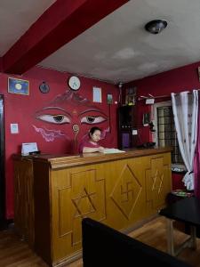 a woman sitting at a counter with a face painted on the wall at Hotel Sweet Dreams thamel kathmandu in Kathmandu