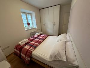 Val di Non Apartment في كليس: غرفة نوم بسرير وبطانية حمراء وبيضاء