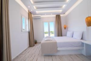 a white bedroom with a bed and a window at Depis Edem private villas naxos in Plaka