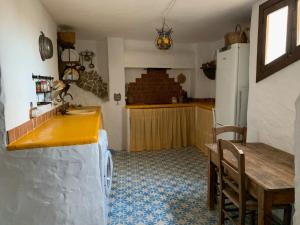 cocina con encimera, mesa y nevera en Antigua Aljibe, en Espera