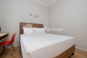 a bedroom with a white bed and a red chair at Palm Eight Mitra RedDoorz in Jakarta