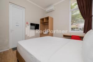 a bedroom with a white bed and a window at Palm Eight Mitra RedDoorz in Jakarta