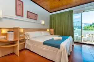 a bedroom with a bed and a desk and a window at Hotel Xaine Park in Lloret de Mar