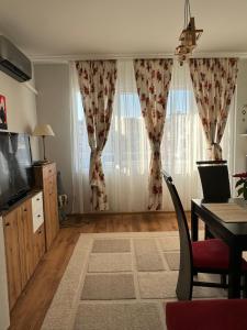 a living room with a table and a television and curtains at The Master and Margarita Apartment, Майстора и Маргарита, two bedroom apartament in Burgas