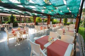 a restaurant with tables and chairs under a roof at MIR'AMOR GARDEN Resort Hotel-ALL INCLUSIVE in Antalya
