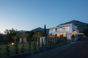 een groot wit huis bij zonsondergang met bergen op de achtergrond bij 5-Star Villa Calma I with Heated Pool, Jacuzzi, Sea and Palm Tree Garden in Starigrad-Paklenica