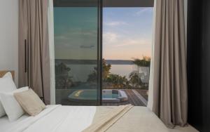een slaapkamer met een bed en een groot glazen raam bij 5-Star Villa Calma I with Heated Pool, Jacuzzi, Sea and Palm Tree Garden in Starigrad-Paklenica